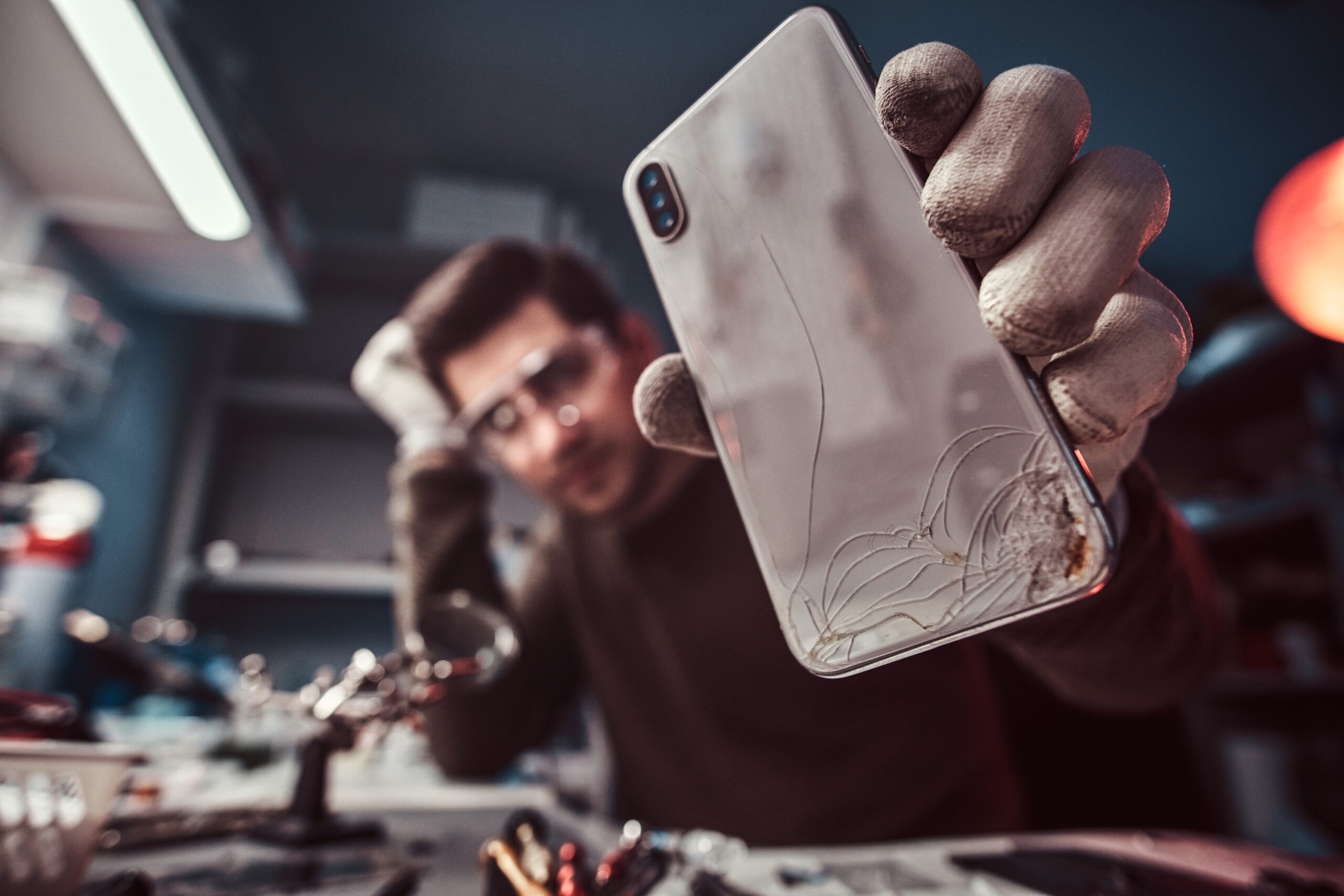 Electronic technician showing a modern smartphone with a broken body